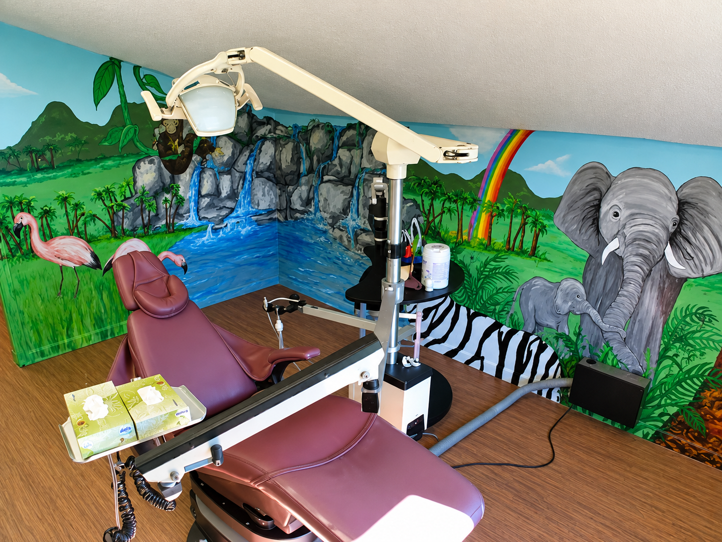 Our children’s dental room with a jungle mural, elephant, rainbow, and dental chair